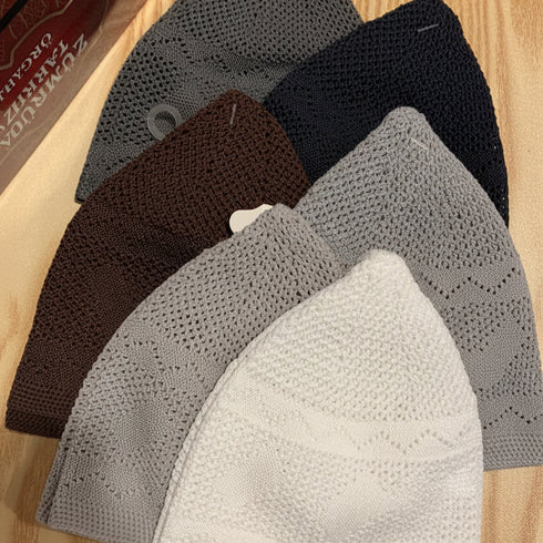 Set of five triangular face masks in black, gray, brown, and white on a wooden surface.